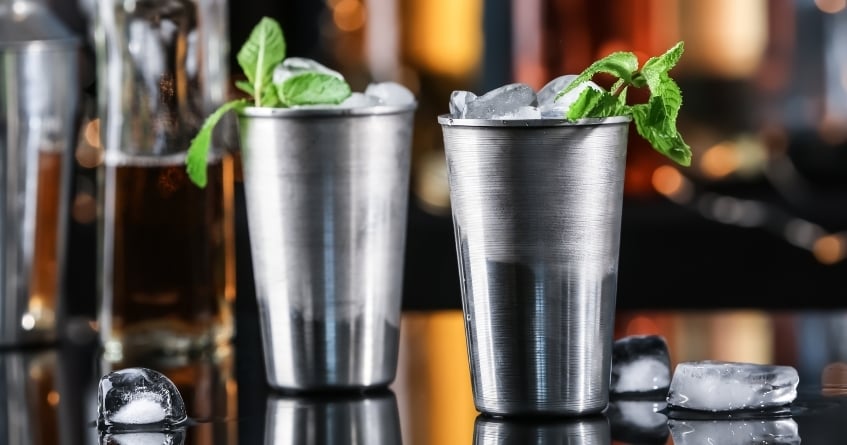 Two stainless steel julep cups filled with crushed ice and mint garnish, highlighting the traditional presentation and temperature control of Mint Juleps and similar cocktails.