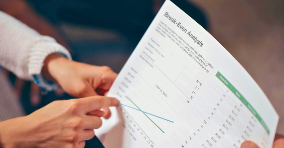 Close-up of hands pointing at a break-even analysis chart from a restaurant business plan — financial planning for restaurant business.