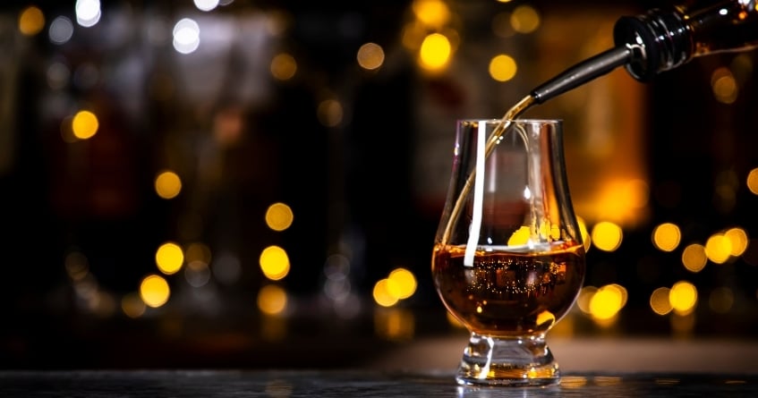 Whiskey being poured into a Glencairn glass, highlighting the tulip-shaped design that concentrates aroma and enhances the tasting experience.