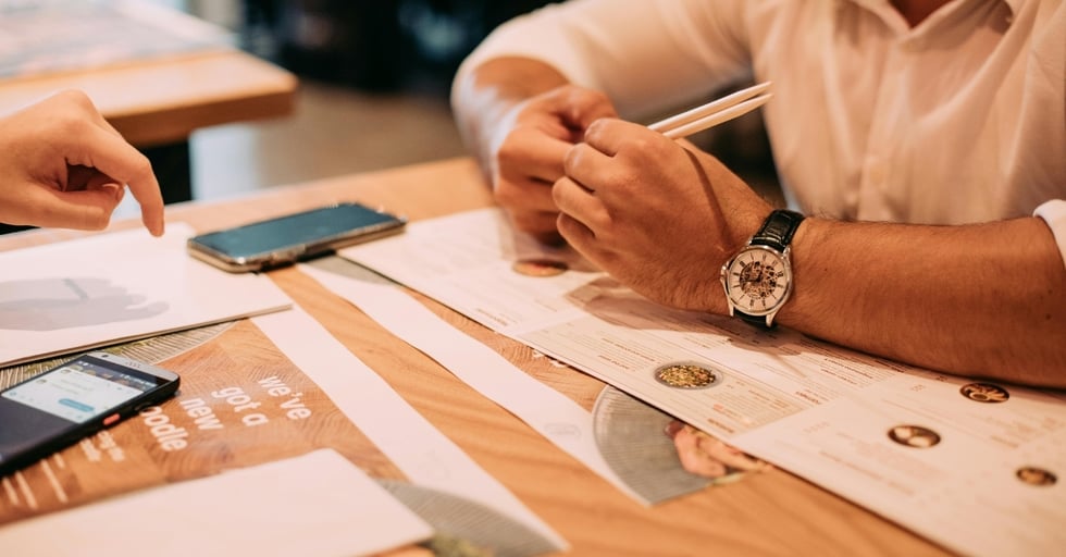Restaurant manager reviewing menu with colleague during meeting.