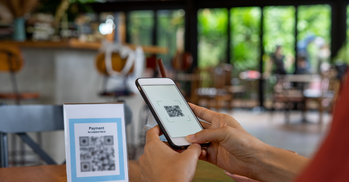 Customer using smartphone to scan QR code for contactless restaurant payment.