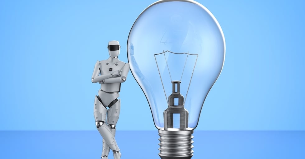 Robot standing next to a large light bulb on a blue background.