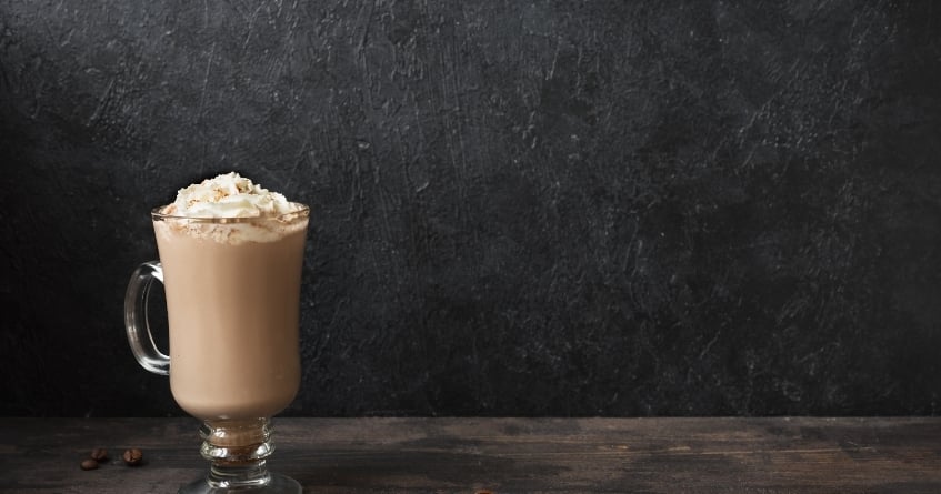 Irish coffee mug filled with a creamy hot cocktail, topped with whipped cream — an example of proper glassware for heated drinks and layered presentation.