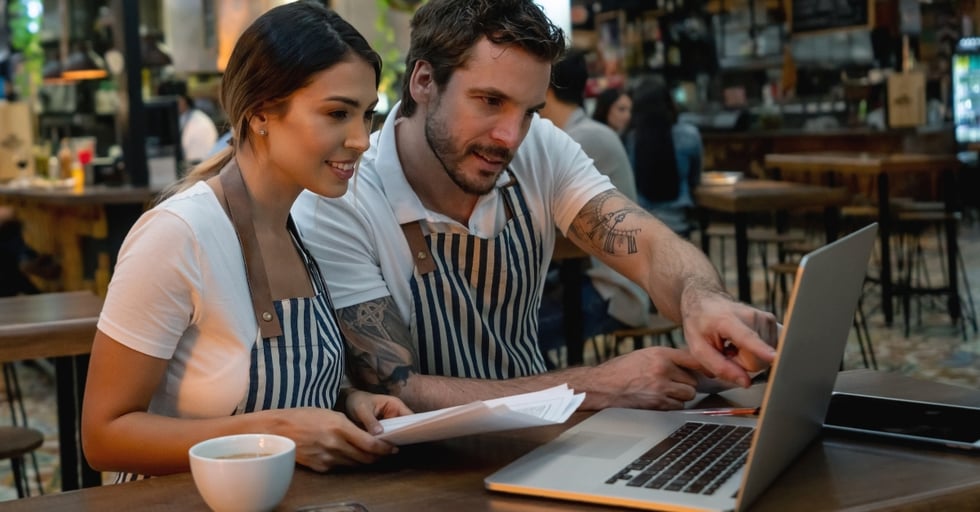 Bar owners at table looking at laptop
