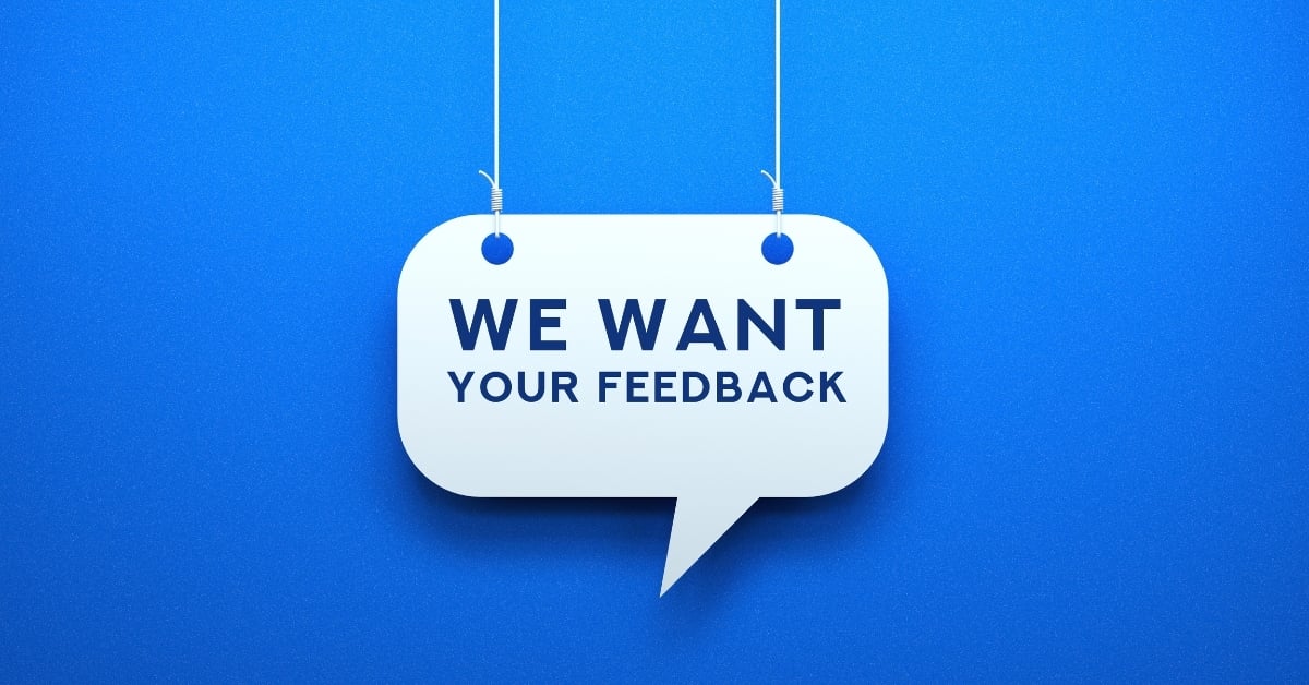 Speech bubble sign reading “We Want Your Feedback” on blue background, encouraging customer input and engagement.