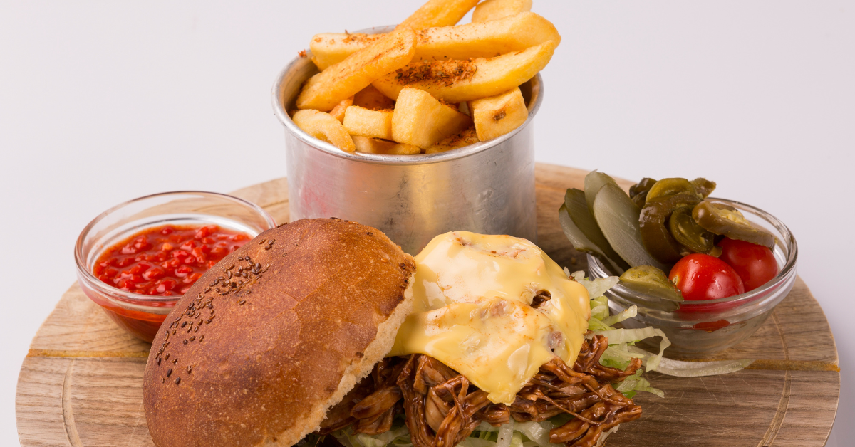 Casual meal with pulled pork burger, fries, and condiments — understanding portion sizes and menu mix is critical for controlling food waste and COGS.