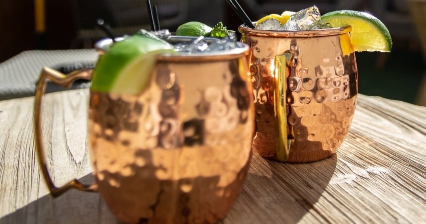 Two copper mugs filled with ice and garnished with lime, showcasing the iconic presentation and temperature retention of Moscow Mule cocktails.