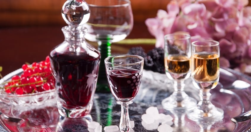Snifter glass filled with dark brandy on a reflective bar top, illustrating how bowl shape traps aroma and elevates spirit-forward service.