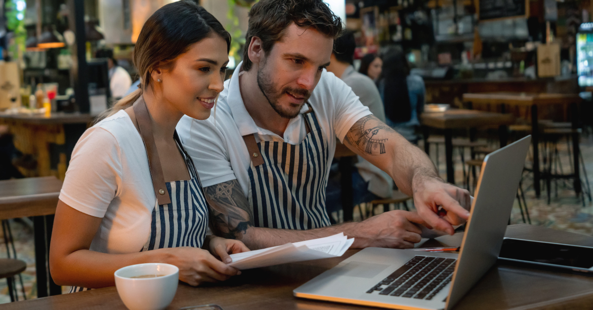 Restaurant owners reviewing sales data on laptop to improve profitability and optimize peak hour performance