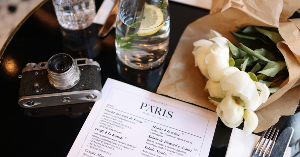 Restaurant menu with flowers and camera on table — menu pricing concept