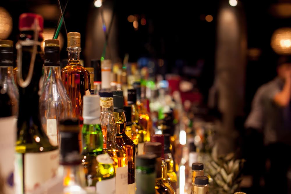Liquor inventory management: numerous liquor bottles arranged on bar shelves.